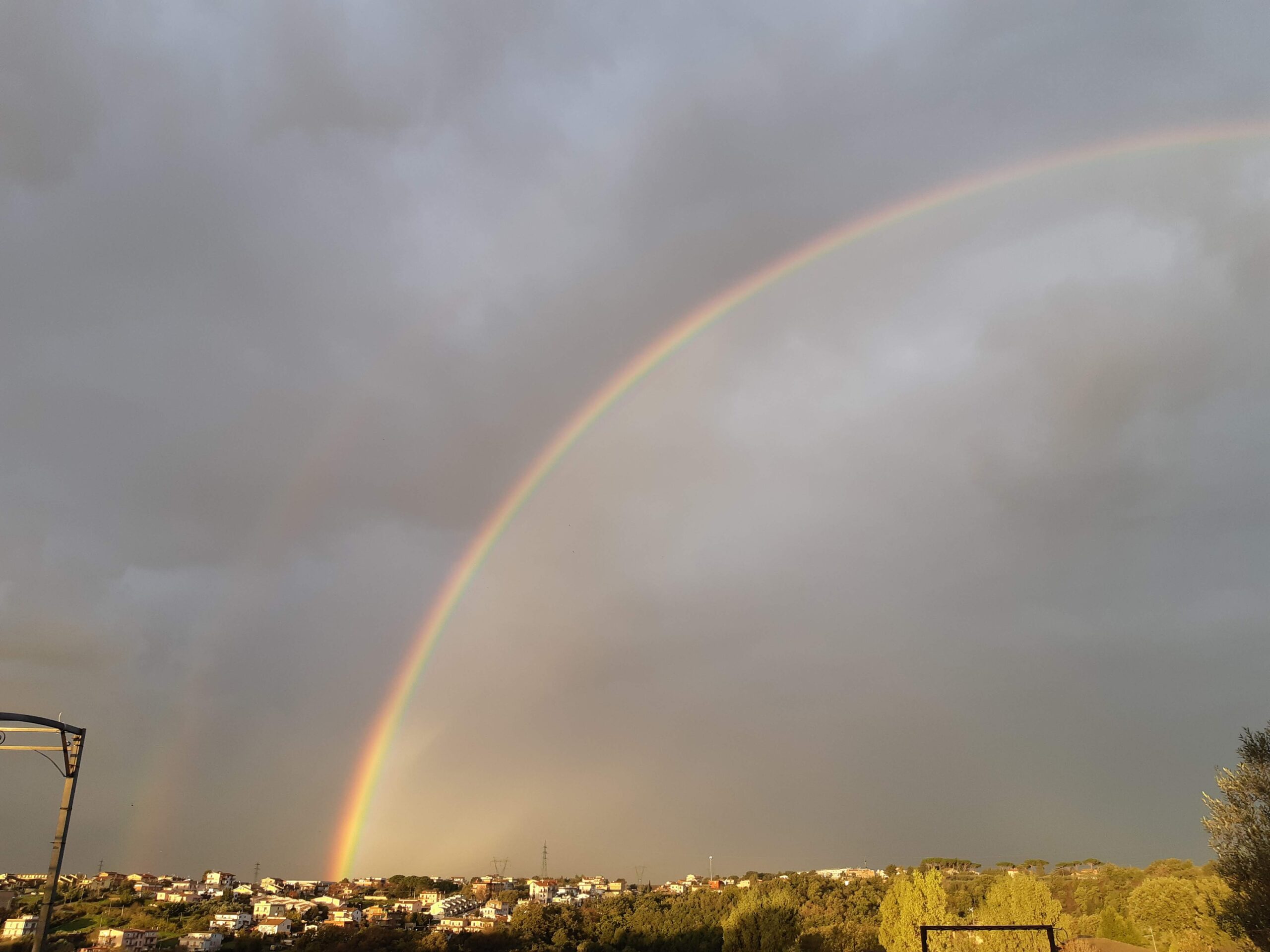 Immagine di un ampio arcobaleno su un piccolo centro abitato. Ecco un "apophthegma": la vita, come un arcobaleno, è fatta di tanti colori, ma non si vede dove va a finire. Le parole della filosofia rock stoica sono strumenti del lavoro per la cura di sé.