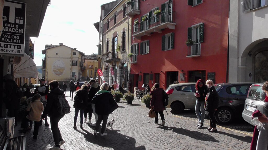 Immagine di uno slargo affollato (con acciottolato) in un borgo italiano. La libertà (eleutheria) è tale solo quando ben regolata dal singolo e dalla società, altrimenti è capriccio e anarchia. Le parole della filosofia rock stoica sono strumenti del lavoro per la cura di sé.