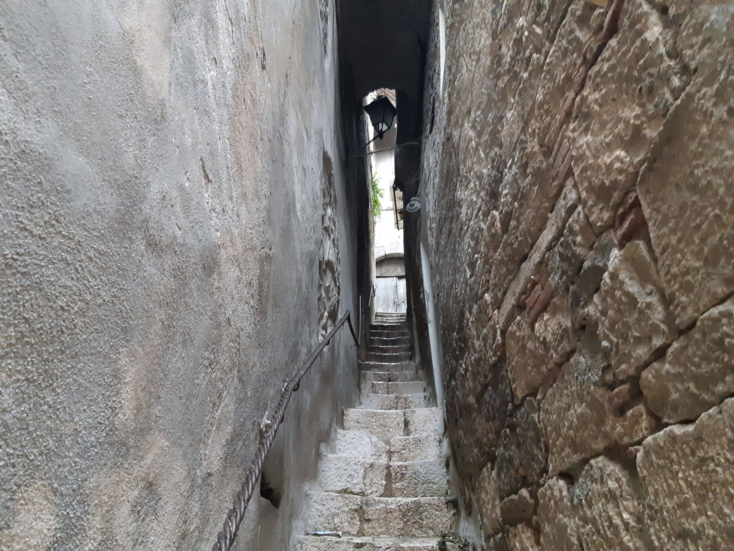 Immagine dal basso verso l'altro di un vicolo molto stretto (con una scalinata in pietra) in un antico borgo italiano. Un desiderio può essere molto intenso e grande, ma la strada per soddisfarlo è spesso stretta e impervia. Orexis significa inclinazione, desiderio.