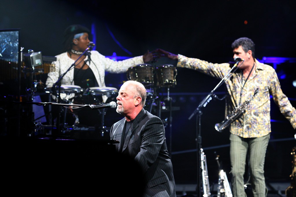 Immagine di Billy Joel, non più ragazzino, ripreso durante un concerto mentre suona il pianoforte e canta (“Billy Joel Live!” by minds-eye is licensed under CC BY-NC-ND 2.0).