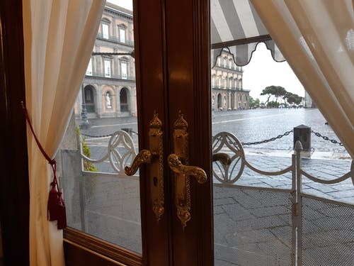Immagine di un dettaglio di Piazza del Plebiscito a Napoli vista attraverso una porta a vetri chiusa del Caffè Gambrinus. Possiamo solo sbirciare oltre le porte della limitata condizione umana e sperare di scorgere qualche verità. Foto di Carlo de Blasio. Cosa pensiamo (della realtà) rientra nel quadro della filosofia di vita rock stoica per la cura di sé.