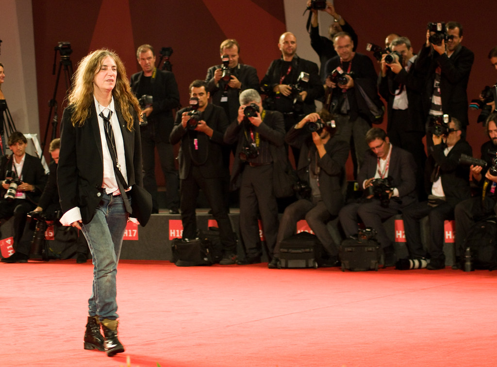 Immagine di Patti Smith ripresa mentre cammina su un red walk con una moltitudine di fotografi sullo sfondo (“04092011-DSC_1590” by brixton21 is licensed under CC BY-NC-ND 2.0). La musica rock è una filosofia di vita.