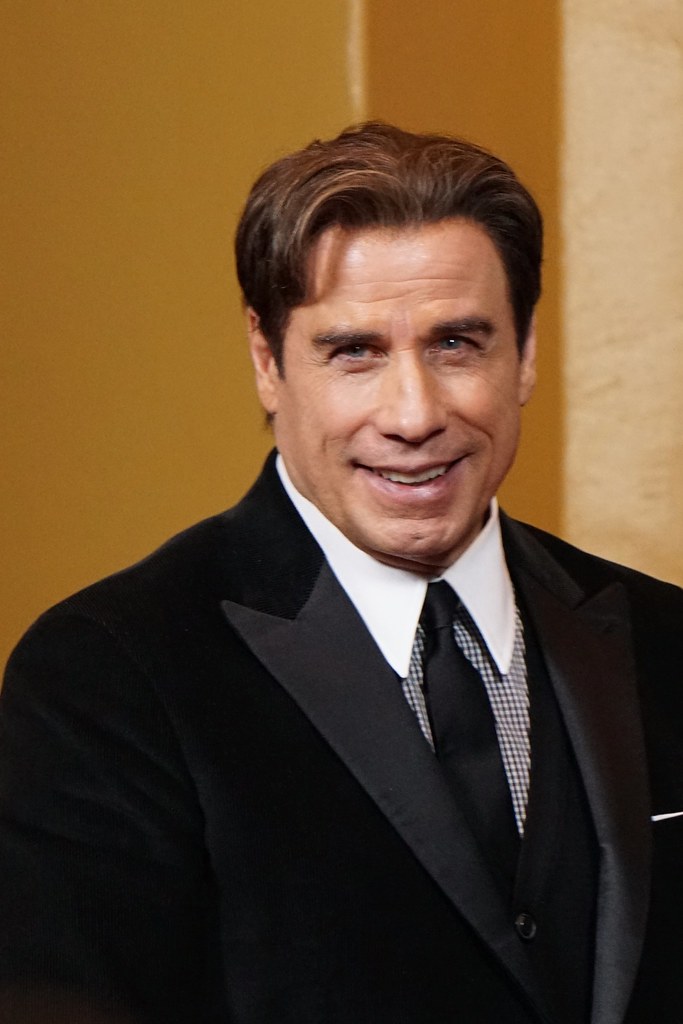 Immagine di John Travolta sorridente in abito da sera (“John Travolta” by J_Jacks1985 is marked with CC BY-NC 2.0).