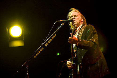 Immagine di Neil Young, non più ragazzino, mentre canta e suona la chitarra durante un concerto (“Neil Young” by yle.fi/pop is licensed under CC BY-NC-SA 2.0). La musica rock è una filosofia di vita.