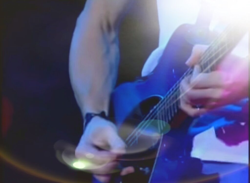 Immagine ravvicinata di una chitarra ripresa in un momento in cui viene suonata da un musicista.