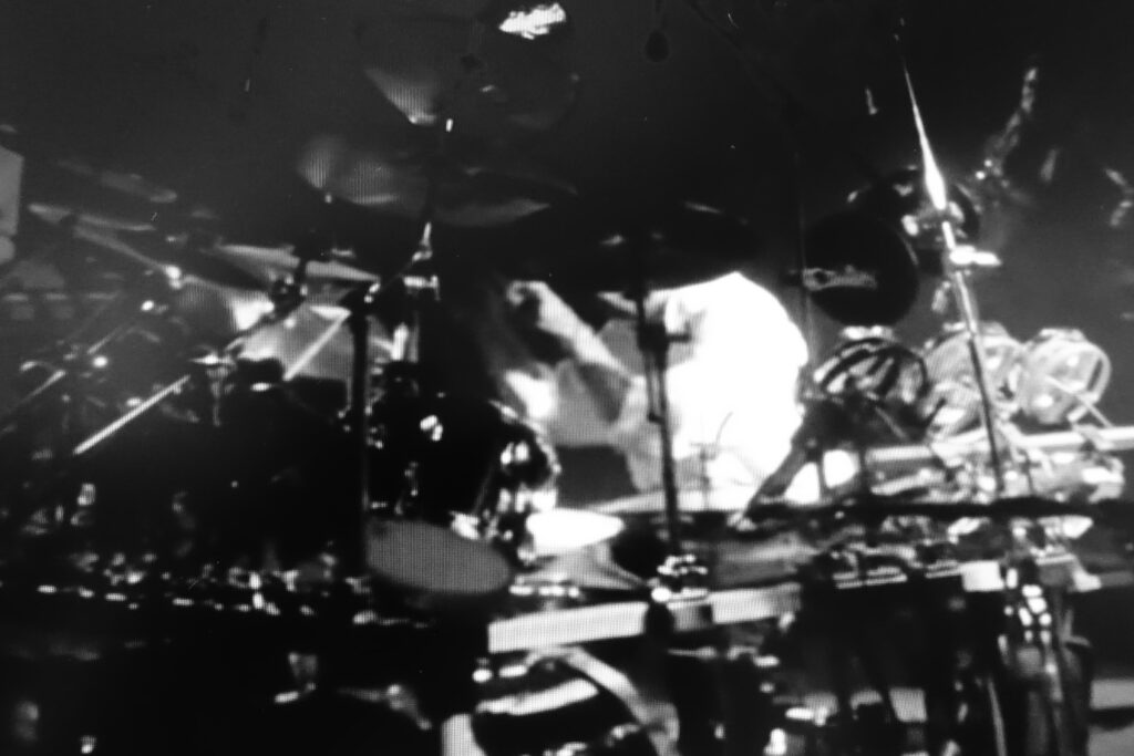Immagine in b/n di una batteria durante un concerto rock.
